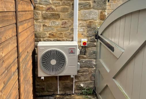 Air conditioning outdoor unit beside a garden gate, Newcastle Air conditioning outdoor unit beside a garden gate fitted by UK Aircon, air conditioning installers serving Newcastle