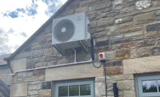 Air conditioning outdoor unit on a stone wall, Cramlington Air conditioning outdoor unit on a stone wall fitted by UK Aircon, air conditioning installers serving Cramlington